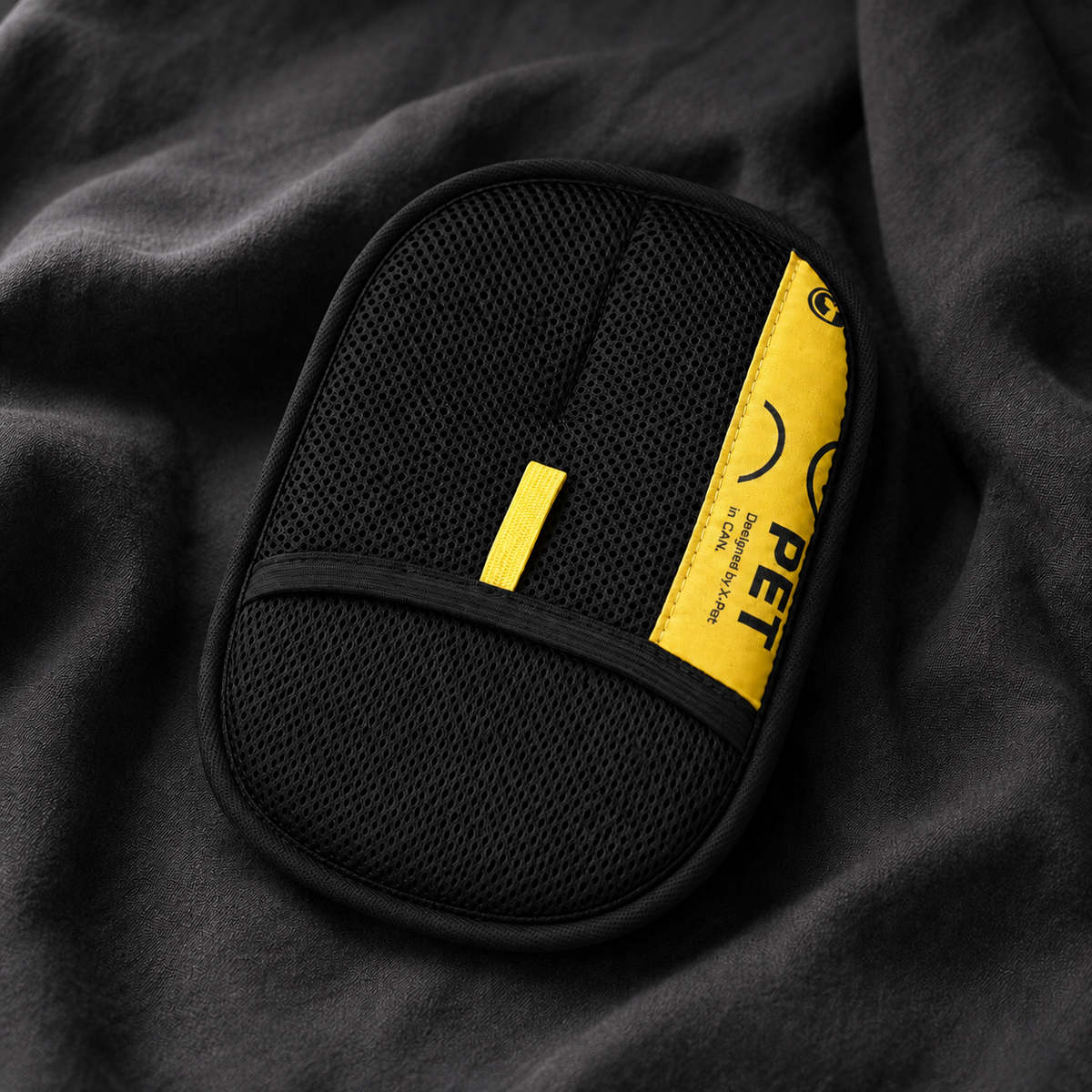 PeTidy pet hair remover mitt lying on dark fabric, front view