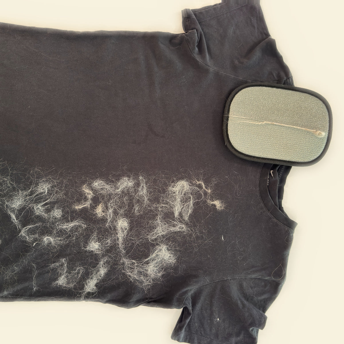 Black T-shirt half covered in cat fur, half clean, with the PeTidy glove palm up showing the fur strip